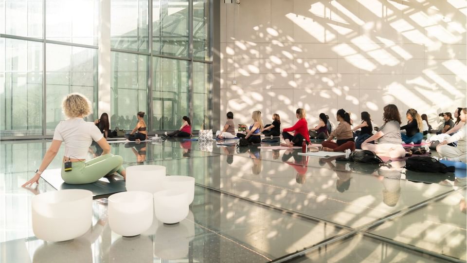 Guests seated on yoga mats during a wellness class by large windows under bright natural light at Hotel X Toronto