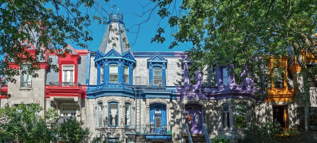 Façades colorées d'un rang de maisons victoriennes sous des arbres au Warwick Le Crystal Montréal