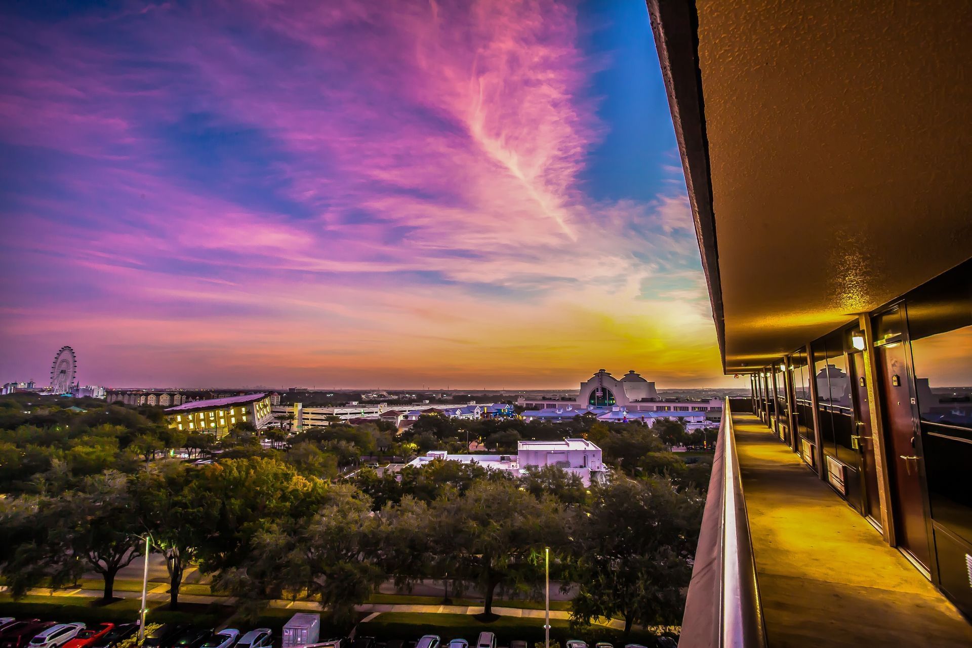 An incredible blue and sunset sky as seen from the outdoor walkway of a Rosen Inn hotel, overlooking glowing nearby attractions.