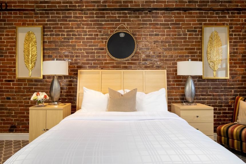 a queen bed with exposed brick walls in chardonnay suite, two en