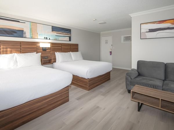 Two queen beds, a couch, and a coffee table in a pet-friendly room at Coast Dawson Creek Hotel.