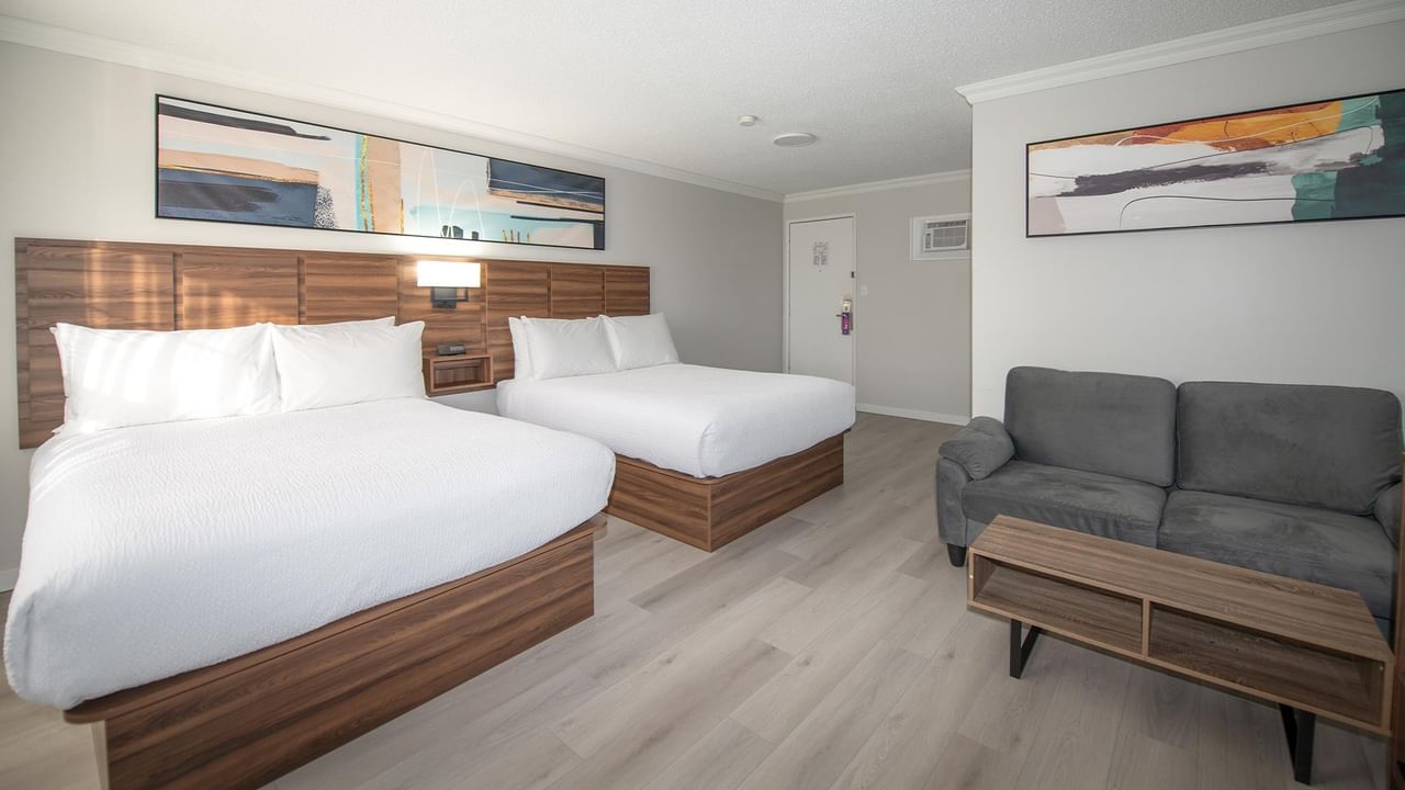 Two queen beds, a couch, and a coffee table in a pet-friendly room at Coast Dawson Creek Hotel.