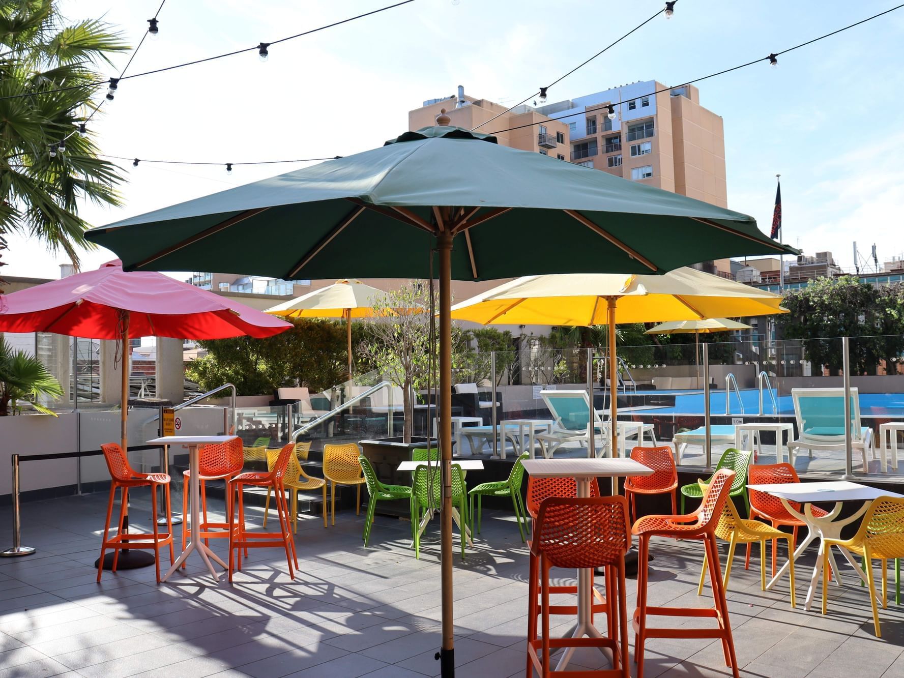 Colorful chairs and umbrellas in outdoor space in poolside at Hotel Grand Chancellor Adelaide