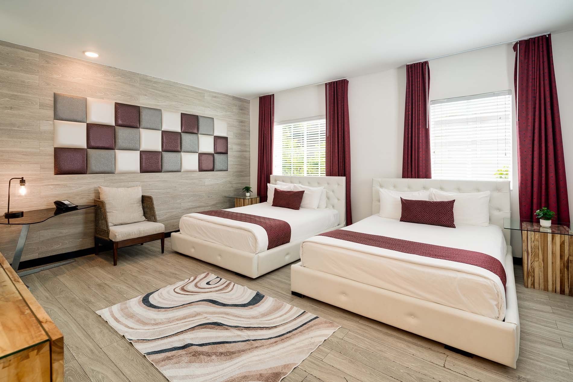 A hotel room with two white beds, red curtains, and a tiled floor
