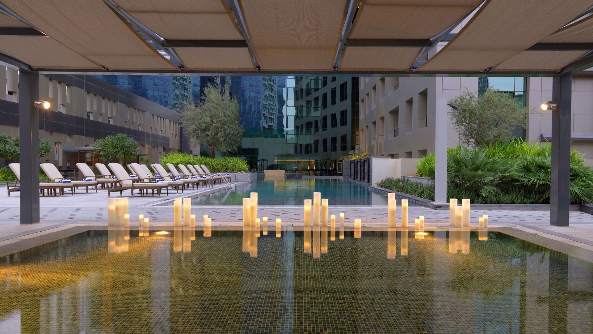 Serene pool with flickering candles floating near the water at DAMAC Maison Cour Jardin
