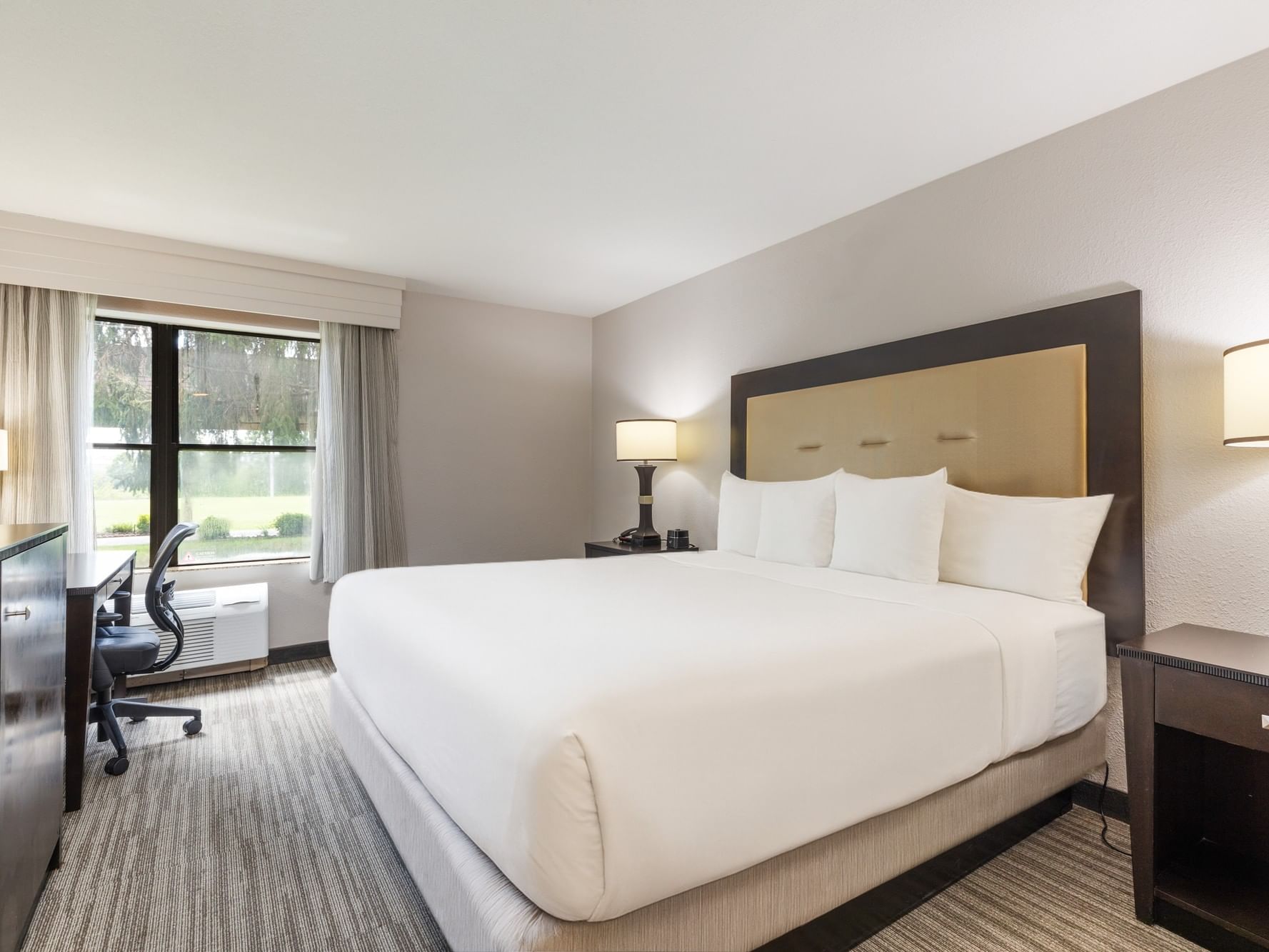 Standar King ADA Access Shower featuring a king bed, tan headboard, and dark wood dresser furniture at Branson Hillside Hotel