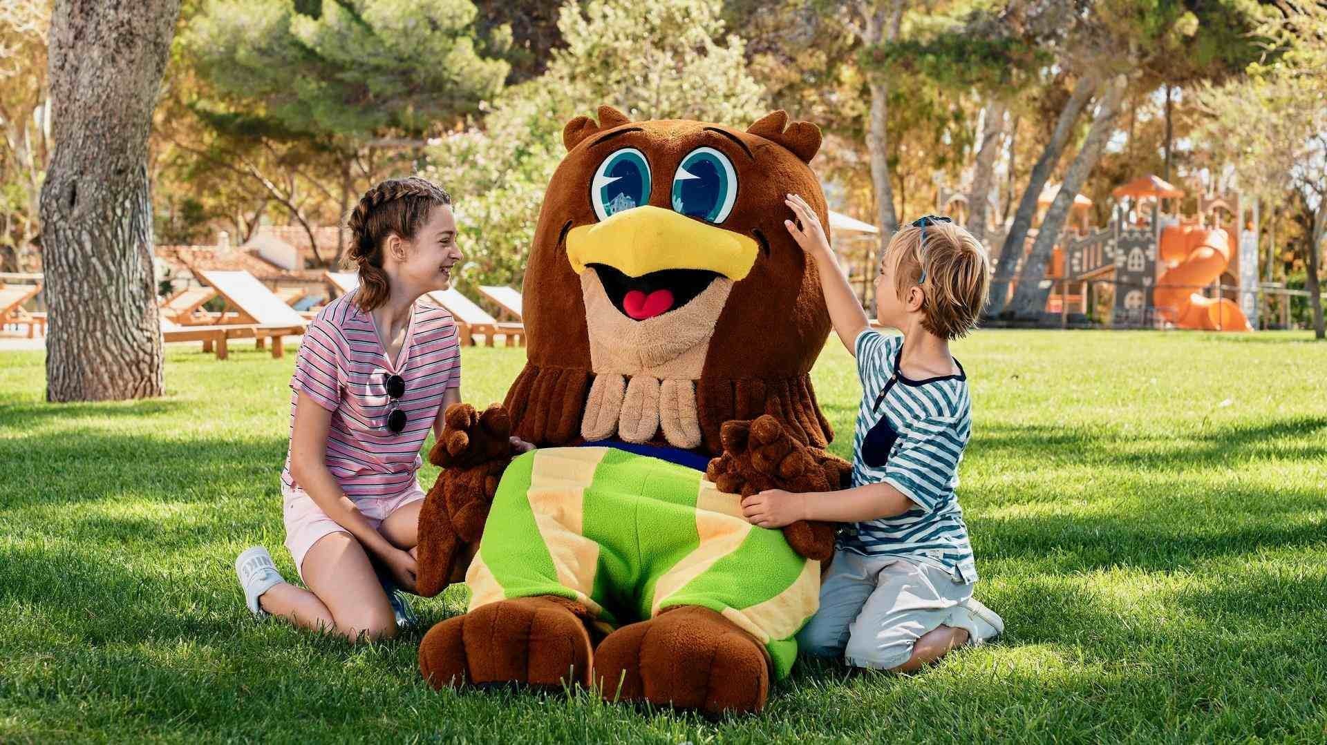 Two children play with a large mascot at Falkensteiner Family Resort Sicily