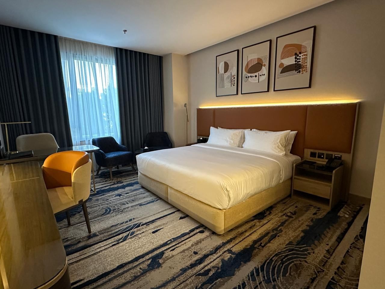 Bed with couches and a work desk by the window in suites at Warwick Jeddah Hotel & Spa