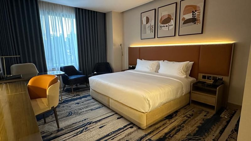 Spacious bedroom with large bed, chairs, and window at Warwick Hotel & Spa Jeddah.