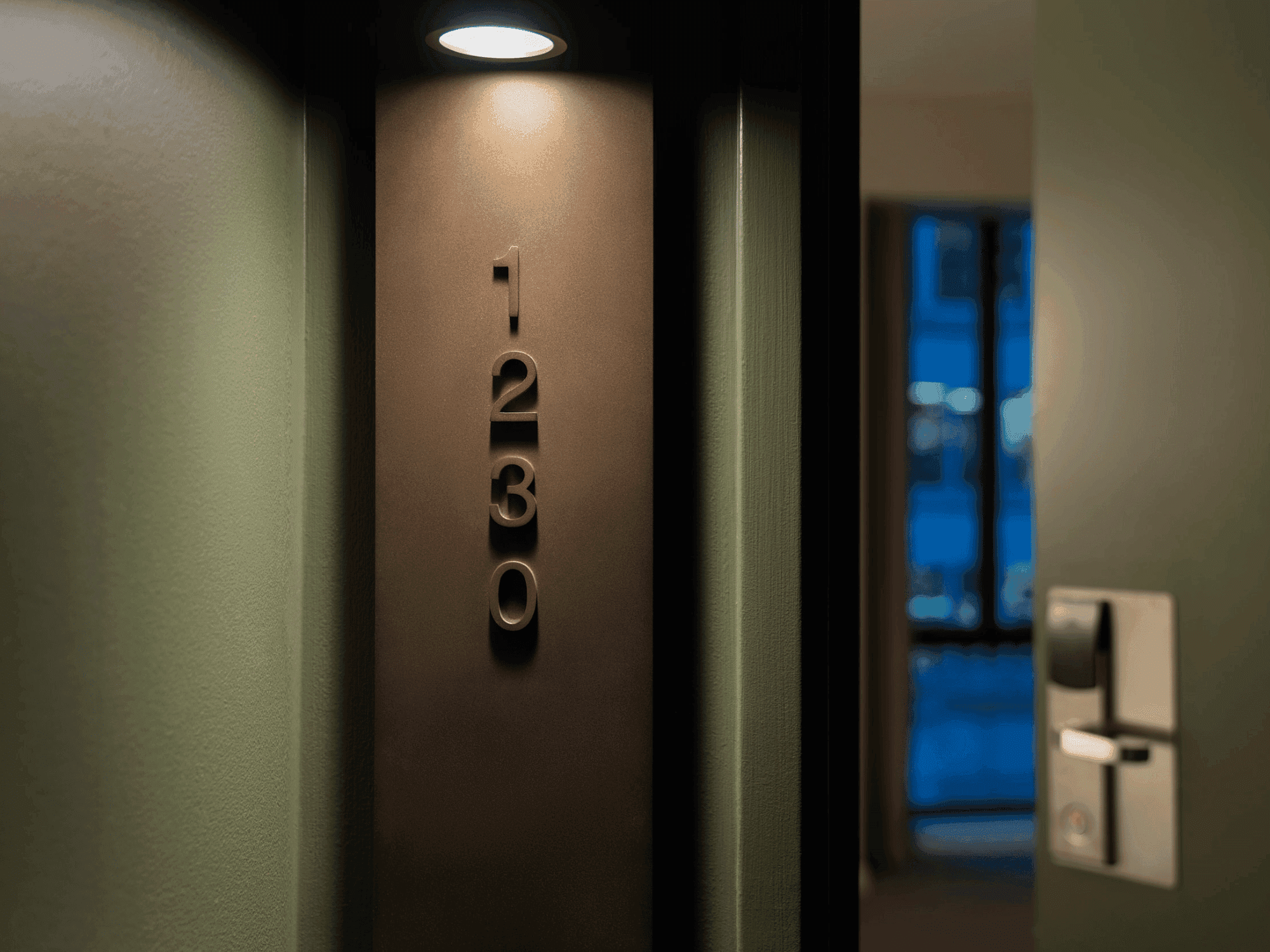 Dark doorway with a lit light above, showing room number 1032, and a partially visible illuminated window.