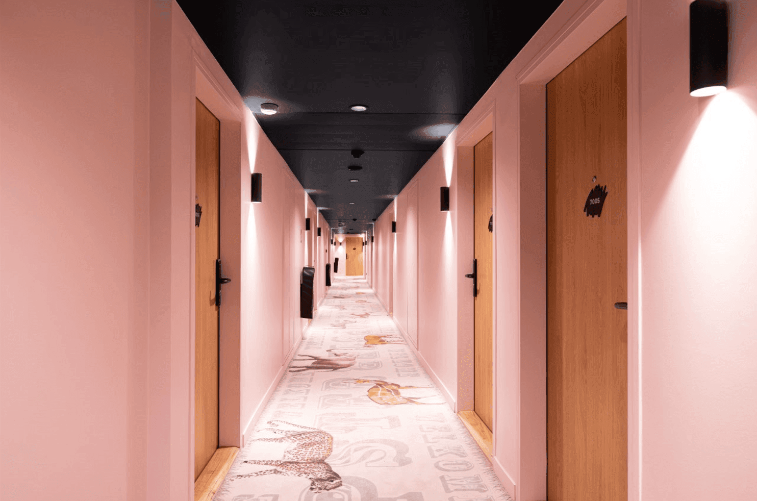 Hallway painted in pink with doors at Kopster Hotel Paris Ouest Colombes