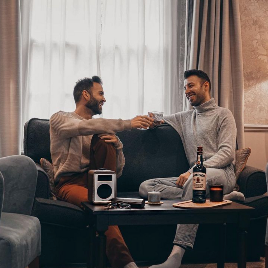 Two men enjoying drinks sitting on a sofa at Richmond Hill