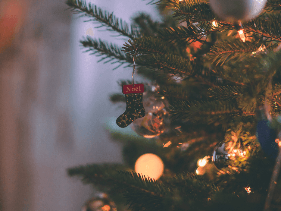 A Christmas tree with a lit-up string of lights and a sock ornament hanging from it at The Sebel Brisbane
