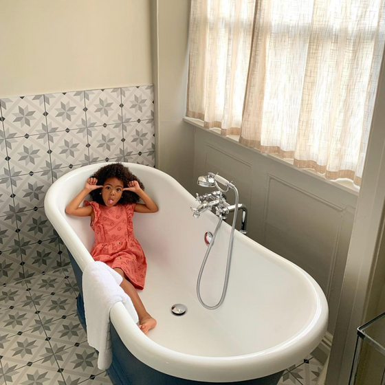 A small girl in a bathtub in a bathroom at Richmond Hill Hotel