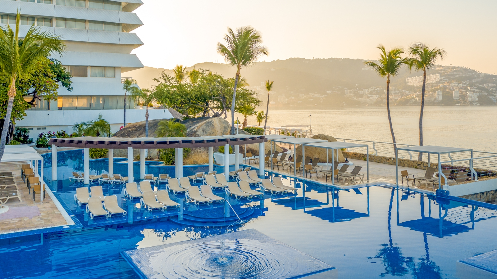 Sunbeds by the pool with an ocean view at FA Acapulco Villas