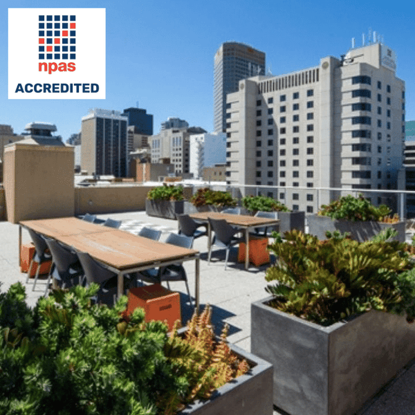Outdoor rooftop dining area with tables, chairs, and large planters at UniLodge Metro Adelaide.