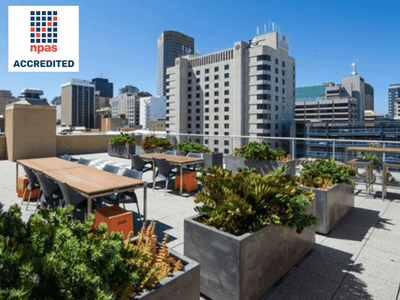 Outdoor rooftop dining area with tables, chairs, and large planters at UniLodge Metro Adelaide.