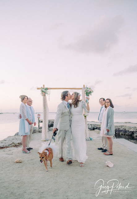 Just married couple kissing while walking dog down jetty at Bayside Inn Key Largo