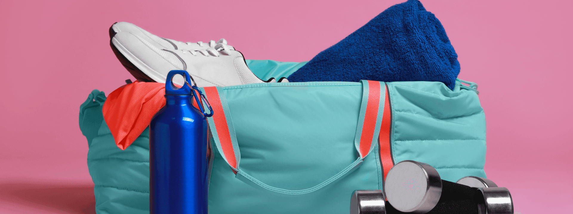 Gym bag with sneakers, water bottle, towel, and dumbbells on a pink background at Polonia Palace Hotel