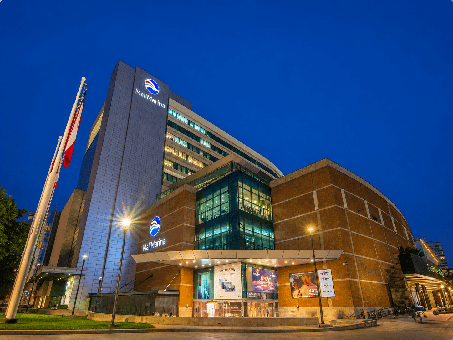 Complejo comercial Mall Marina Arauco iluminado de noche con grandes paneles de letreros cerca de Veranda Hotel