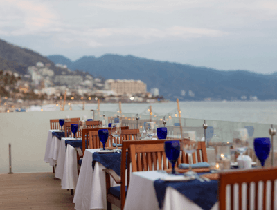 Outdoor dining tables with glasses and plates in Sunset Restaurant at Buenaventura Grand Hotel and Spa
