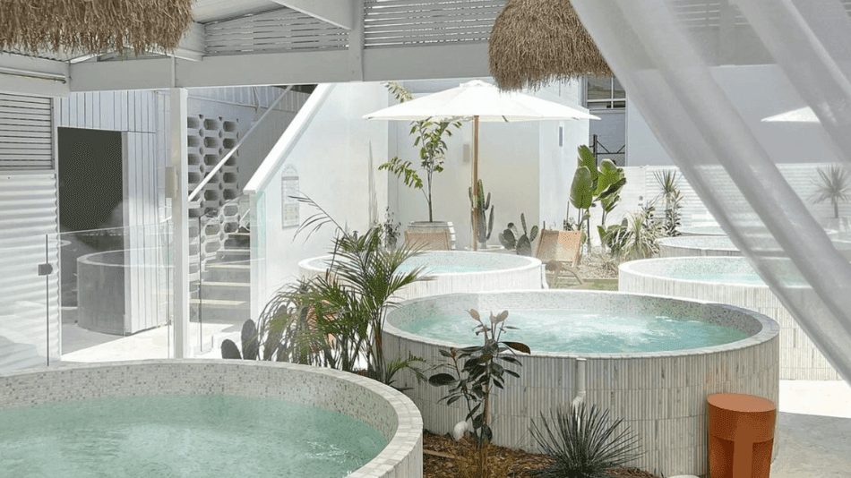 Circular hot tubs surrounded by greenery, with a shaded seating area in a Tank bathhouse at Novotel Sunshine Coast Resort