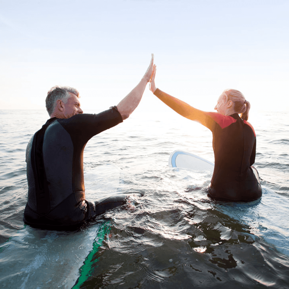 Two people sitting on surfing boards in the middle of the sea near SeaCrest Oceanfront Hotel Pismo Beach