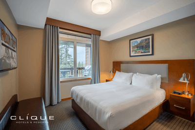 Comfortable bedroom at Falcon Crest Lodge features a king-size bed, a seating area, a large window with a view