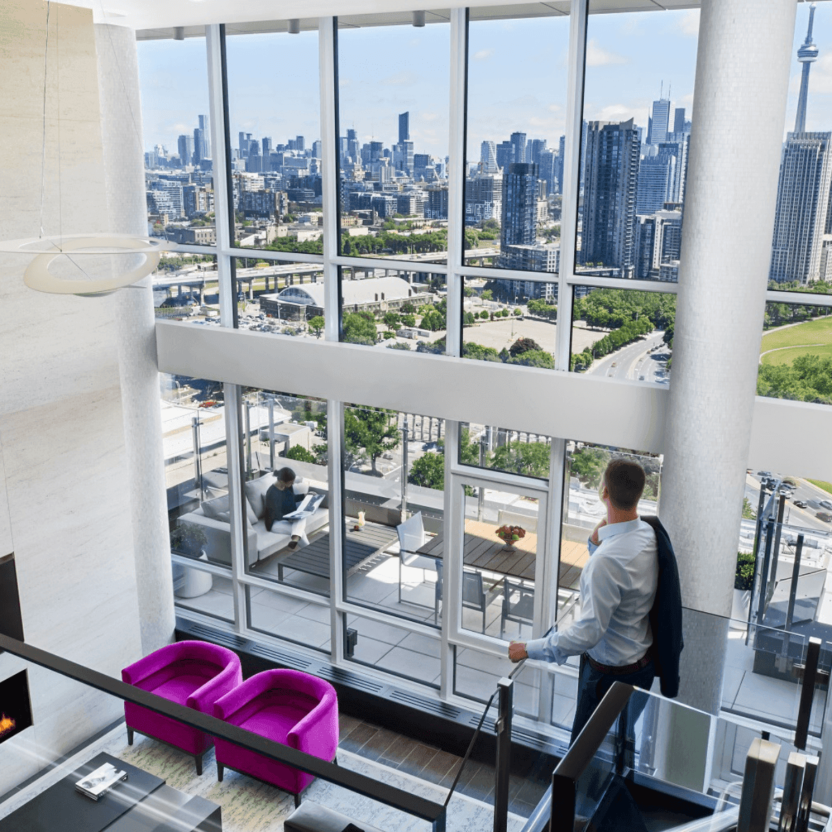 Guest overlooking Toronto skyline and CN Tower in Bi-Level Penthouse Two-Bedroom Suite at Hotel X Toronto