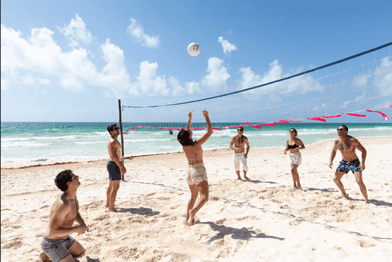 People playing beach volleyball on the beautiful white sand beach with turquoise water at La Zebra Hotel