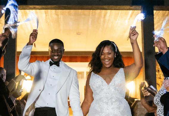 A bride and groom walking hand in hand with guests holding sparklers on either side in Inn at Willow Grove