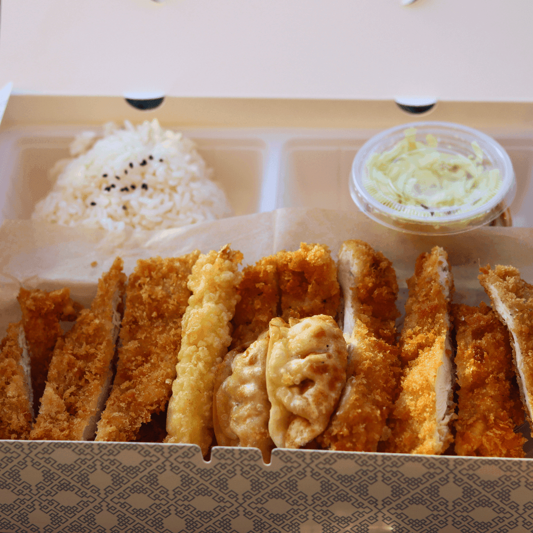 A takeout container with fried chicken, rice, and dumplings.