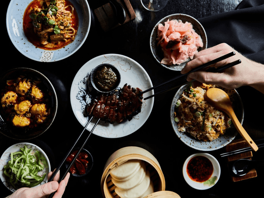 Delicious food prepared on a black table with people helping themselves to eat