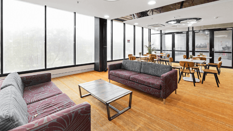 Two couches and a coffee table in a lounge area with large windows.