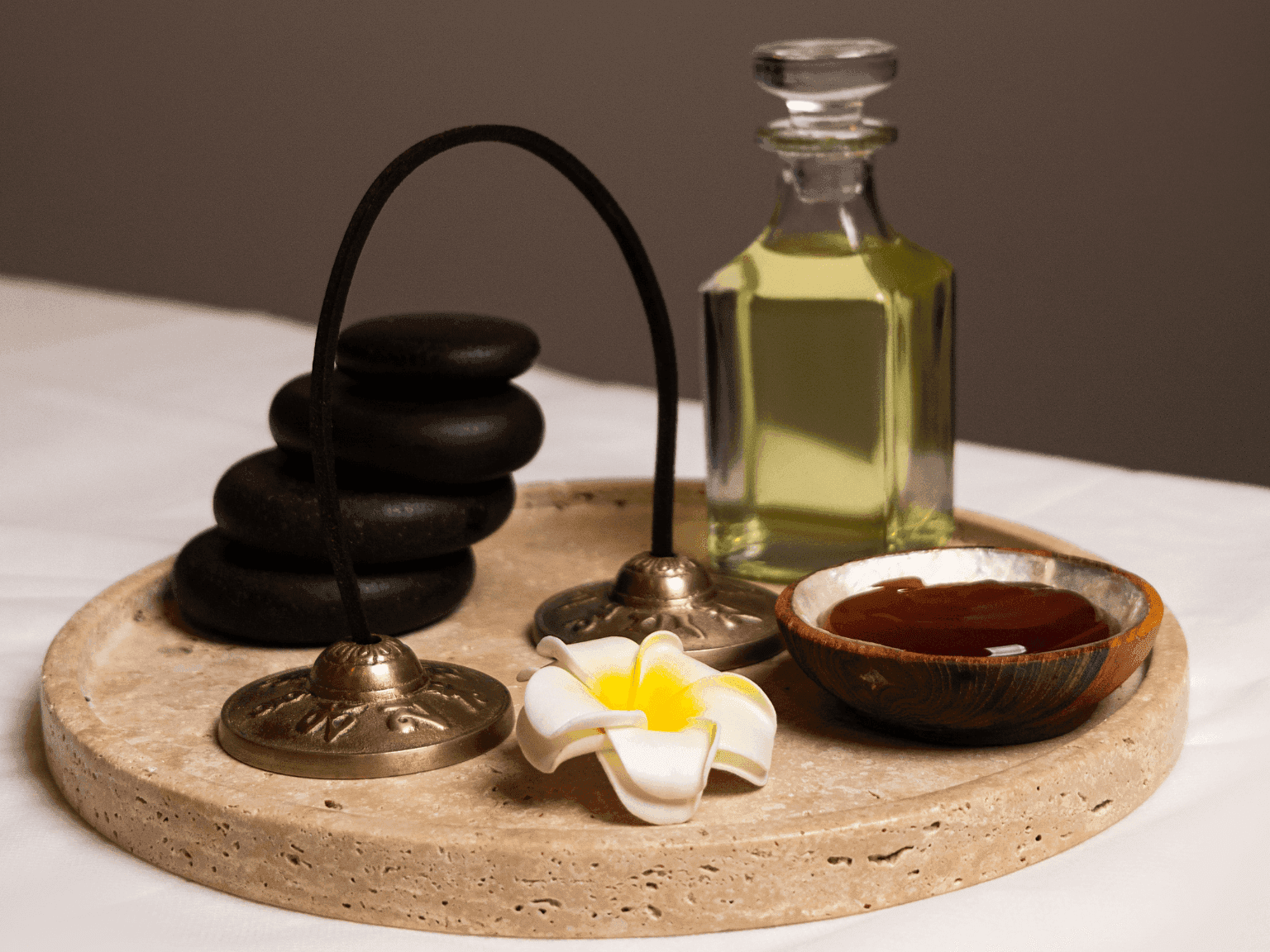 Tray with hot stones, oils, and fresh flowers, creating a serene spa setting in Dreamworks Spa at DAMAC Maison Distinction
