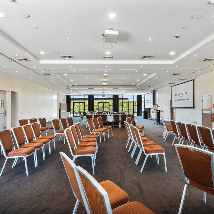 Kooindah Ballroom with rows of orange chairs and a presentation screen at Mercure Kooindah Waters