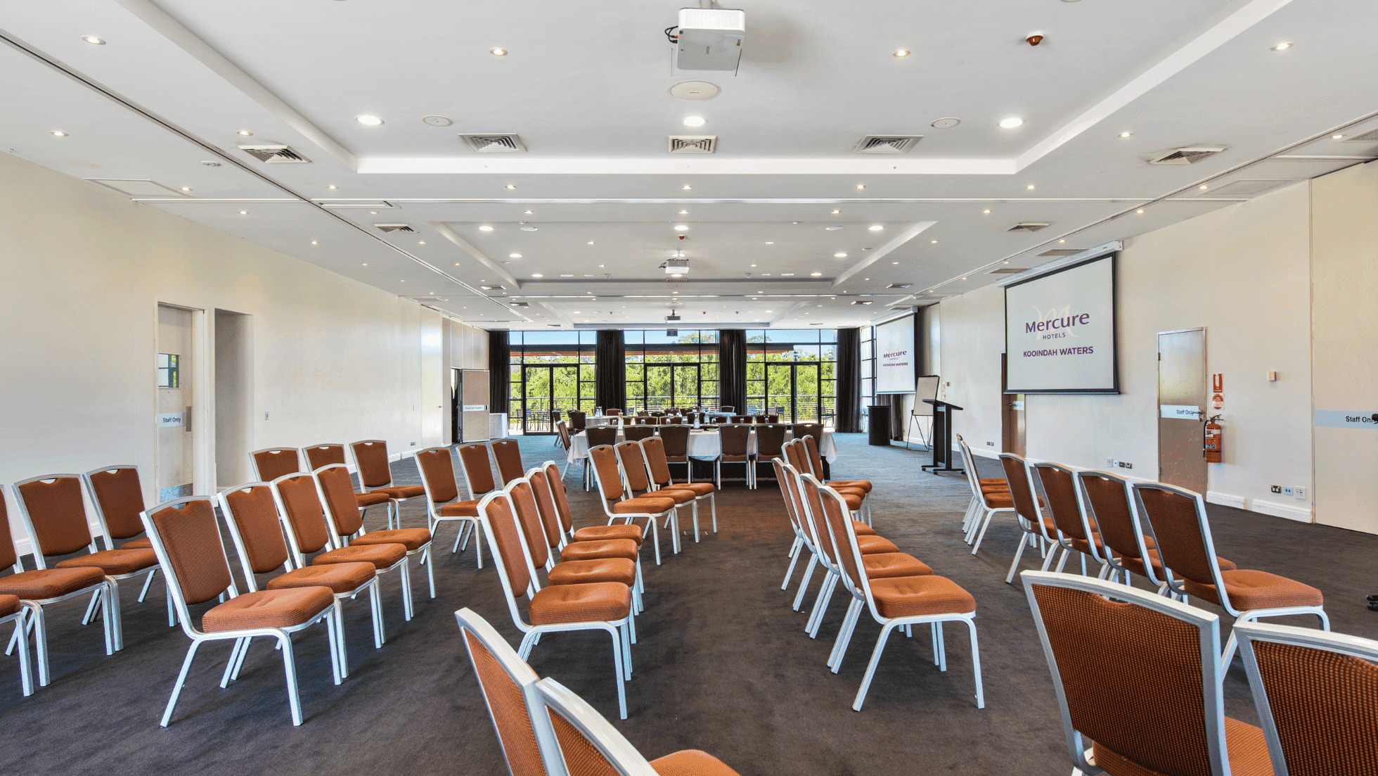 Kooindah Ballroom with rows of orange chairs and a presentation screen at Mercure Kooindah Waters