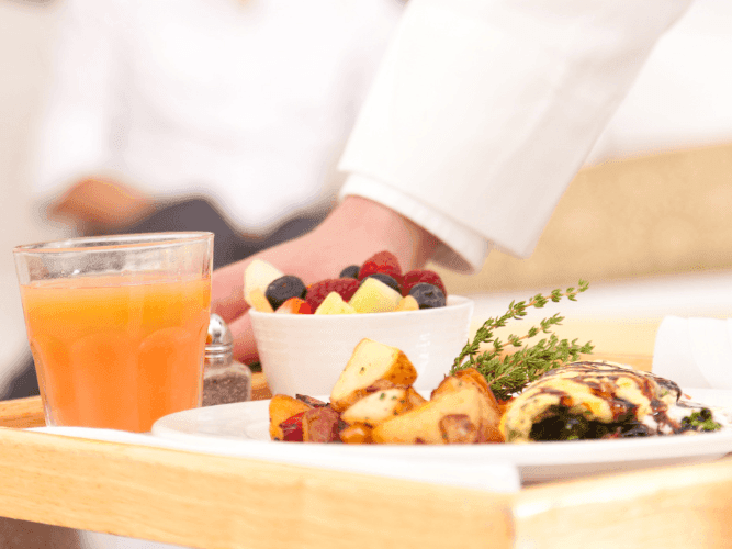 A waiter serving breakfast in a room at Chatrium Hotels