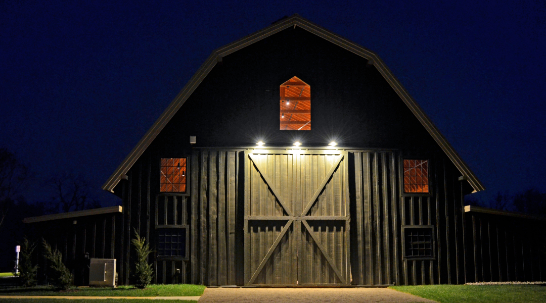 A bride and groom standing at the altar surrounded by loved ones in a rustic barn venue