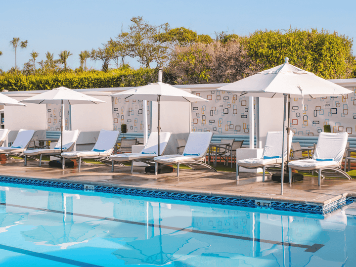 A pool area with white lounge chairs and umbrellas