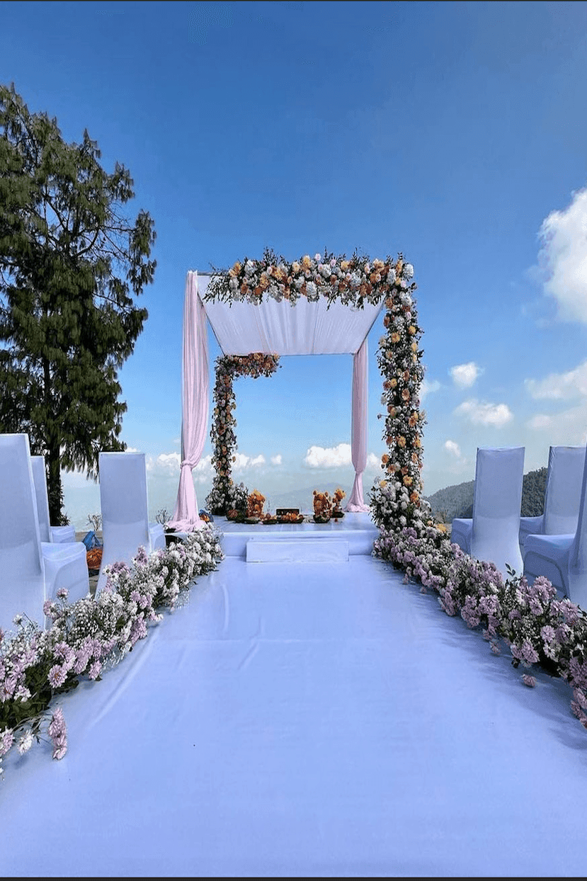 Outdoor wedding setup with floral arch, white chairs, and skyline view at The Terraces Resort & Spa