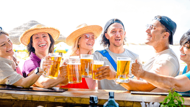 Friends cheering their beer glasses by the bar counter outdoors at Cove Pocono Resorts