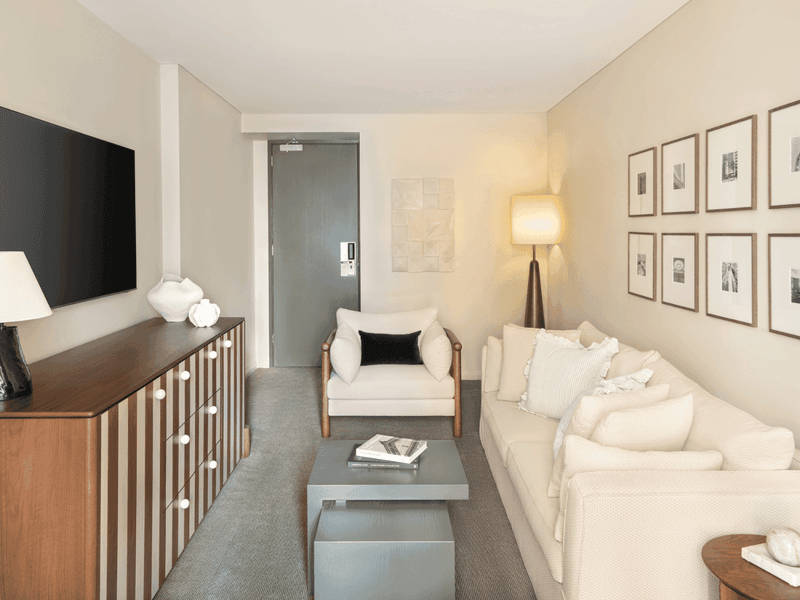 Hotel suite living area with white sofa, gallery wall artwork and flat-screen TV