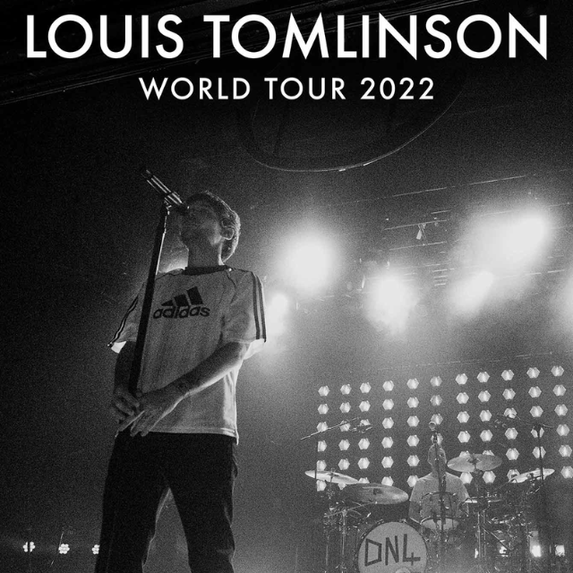 Louis Tomlinson standing at a microphone, world tour banner