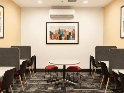 Modern student study lounge with booth seating, red stools, and colorful artwork at Student Living - Waymouth