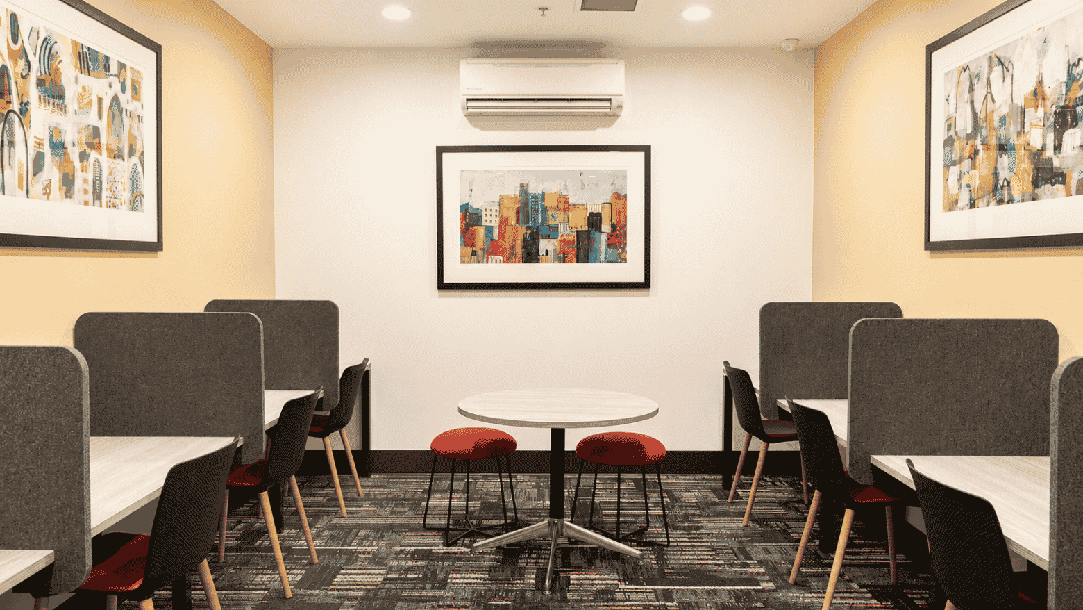 Modern student study lounge with booth seating, red stools, and colorful artwork at Student Living - Waymouth