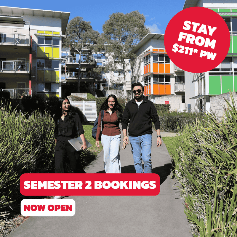 Three people walk on a path past a modern building advertising Semester 2 bookings at UniLodge @ UC - Campus West.