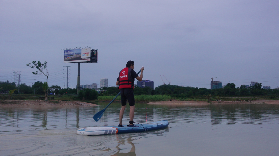 Person paddleboarding on a calm river with an urban view near Sunway Hotel Big Box