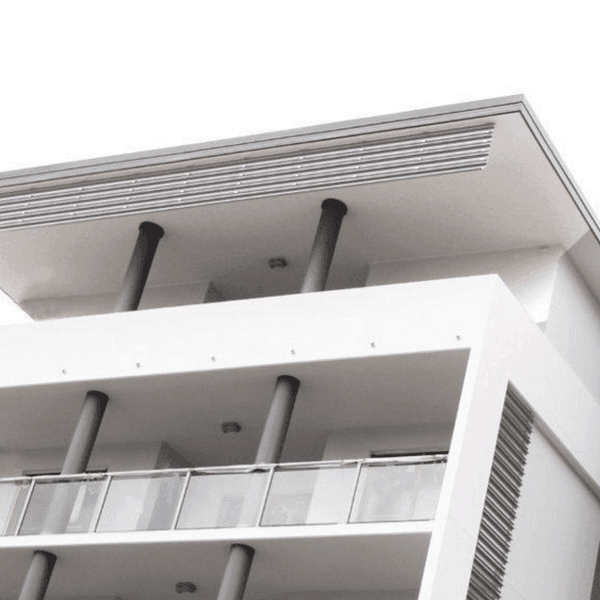 Modern white multi-story building with horizontal louvers and black cylindrical columns supporting balconies.