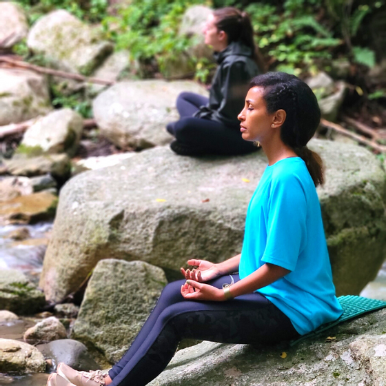 Women meditating by a stream near Honor’s Haven